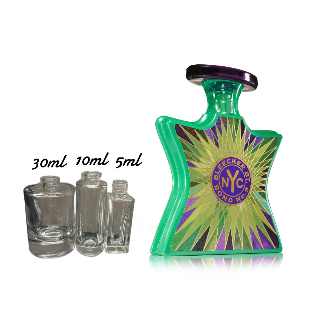 Green perfume bottle with colorful label and smaller clear bottles on a white background